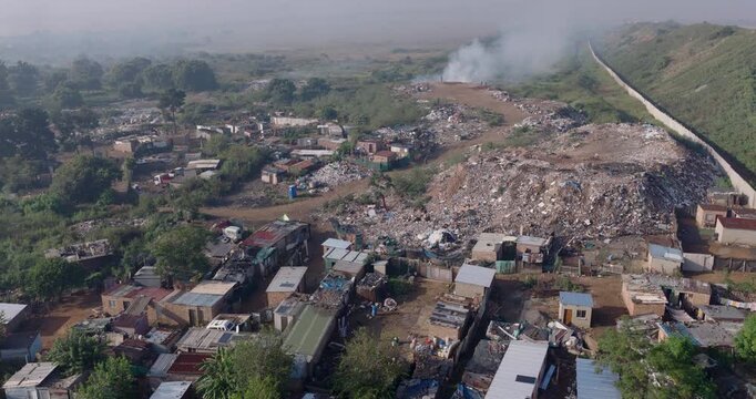 Aerial fly over view. Burning rubbish causing greenhouse gas, contributor to climate change.  Extreme Poverty. People living alongside dumpsite struggling to survive through waste picking.