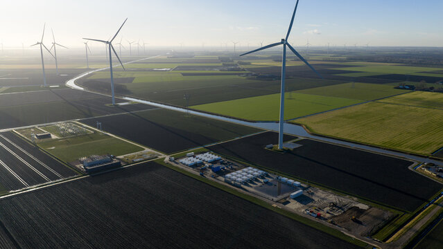 Aerial view of Windplan Groen wind farm with wind turbines, agricultural fields, and a canal in Dronten, Flevoland, Netherlands.