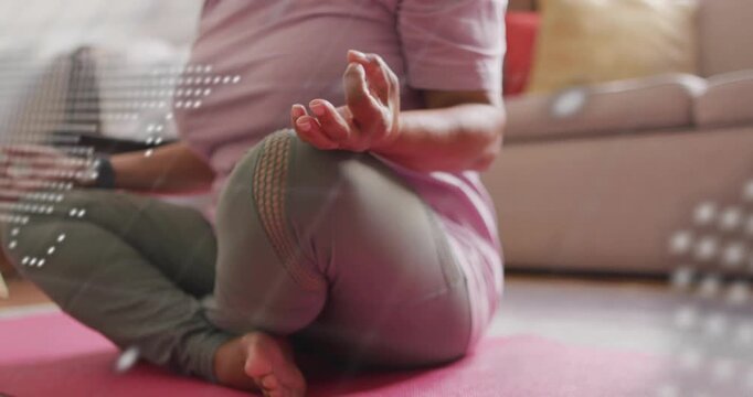 Senior woman forming mudra on pink mat, dotted map and code fading in showing health tech