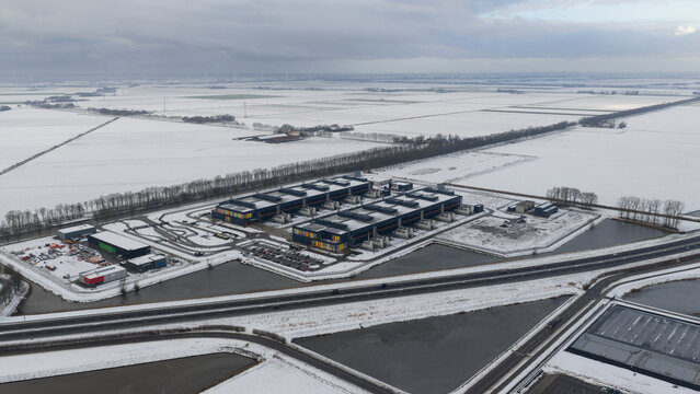 Aerial view of the Agriport a7 datacenter complex surrounded by snow-covered fields and flat winter landscape in Middenmeer, Noord-Holland, Netherlands.