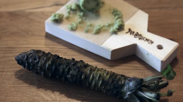 Wasabi root and freshly grated wasabi paste on wooden board, traditional japanese food preparation, cinematic footage