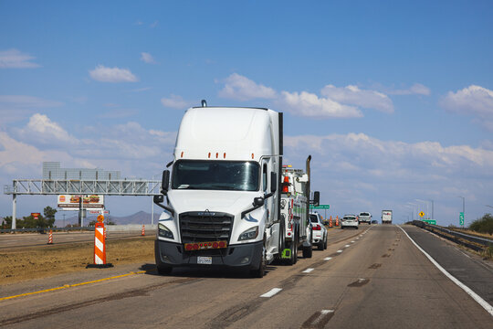 Las Vegas, USA - August 13, 2025: White truck being towed on a busy highway during road construction, with traffic cones, vehicles, and blue sky in the background. Transportation and logistics concept