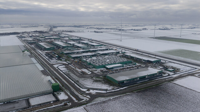 Aerial view of the Agriport a7 datacenter complex with industrial buildings and wind turbines in a snow-covered landscape in Middenmeer, Noord-Holland, Netherlands.