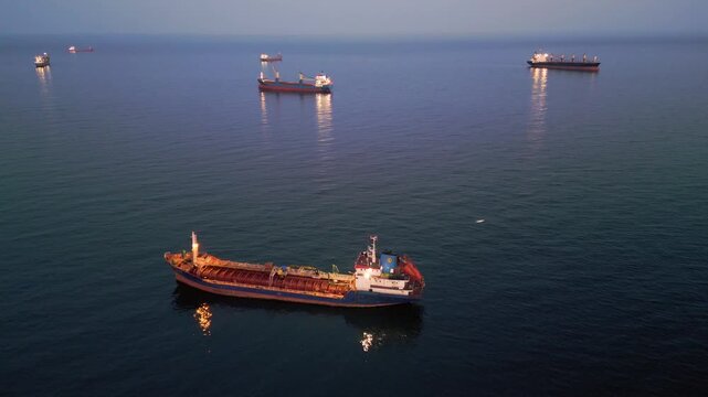 Aerial View of Industrial Tanker Ship at Sea During Sunset with City Lights