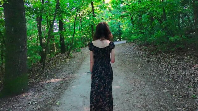Drone tracks a person from above walking along the scenic Normafa woods trail in the Buda Hills. Smooth follow shot through the forest path with bare winter trees and soft light in Budapest, Hungary.