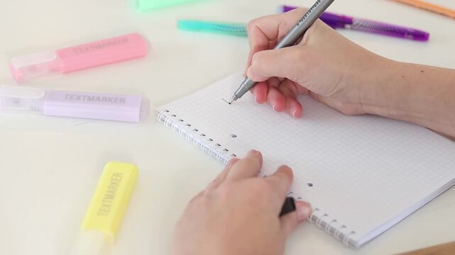 Hand writing plan and checking boxes in notebook on white table