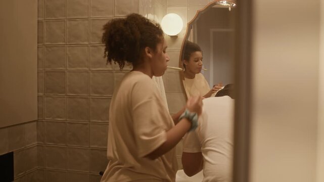 Back view of married young couple spending morning time in bathroom, brushing teeth and fooling around