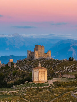 Aerial view of the medieval fortress of Rocca Calascio and the octagonal chapel of Santa Maria della Pieta on a mountain ridge at sunset Calascio, Abruzzo, Italy.