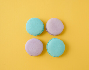 Obraz premium Assorted French macarons on bright yellow background, sunny and cheerful food composition for bakery banner