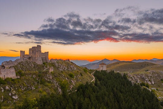 Aerial view of the medieval fortress of Rocca Calascio and the Church of Santa Maria della Pieta on a rocky ridge at sunset in Calascio, Abruzzo, Italy.