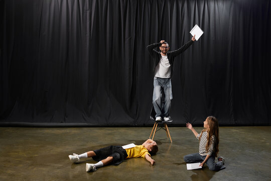 Stylish male tutor guides young students in creative theater performance fun