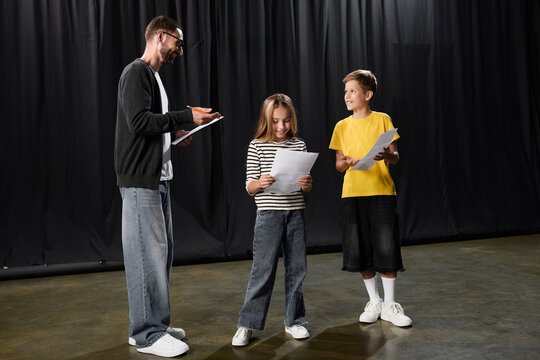 Stylish male tutor guiding children in a fun theater class filled with laughter and creativity
