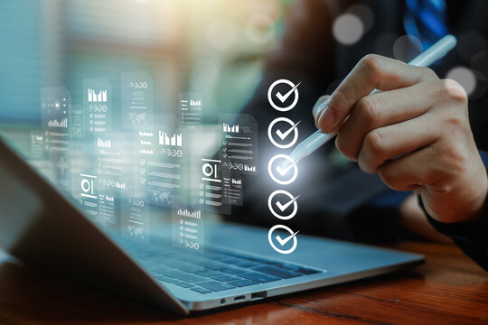 Business professional using stylus on laptop with digital checklist interface, data analytics dashboard, task management, workflow automation, project planning and modern business technology concept.
