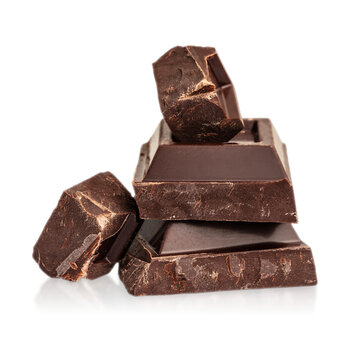 Dark chocolate chunks and bar pieces stacked and isolated background. Clean cutout composition with rich texture