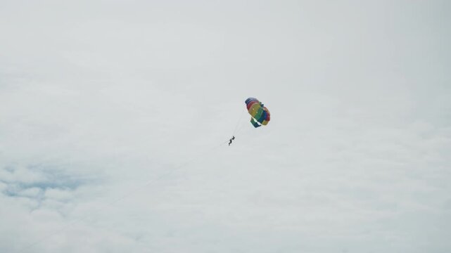 Solo fly above calm waters. Vivid aerial journey over serene seascape with colorful parachute. Lively sky adventure featuring solo parasail drifting peacefully over tranquil ocean scenery