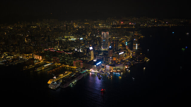 Hong Kong, Hong Kong - 13 February 2026: Aerial view of Victoria Harbour and the Tsim Sha Tsui skyline with illuminated skyscrapers and cruise ships at night in Hong Kong.