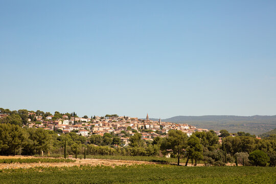 Vue typique sur le village proven&ccedil;al de La Cadi&egrave;re d&rsquo;Azur, panorama du village m&eacute;di&eacute;val perch&eacute; sur la colline, vignes, pins et cypr&egrave;s au premier plan, grand ciel bleu, sud de la France