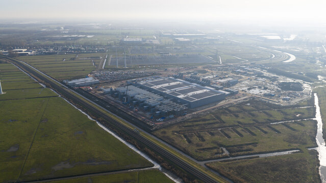 Groningen, Netherlands - 20 January 2026: Aerial view of Datacenter Westpoort featuring a large industrial building with solar panels surrounded by green fields and a railway line.