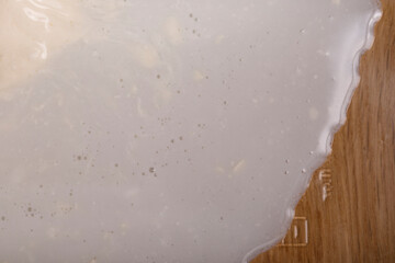 Close up shot of creamy liquid on wood, creating an abstract and intriguing texture. © vegefox.com