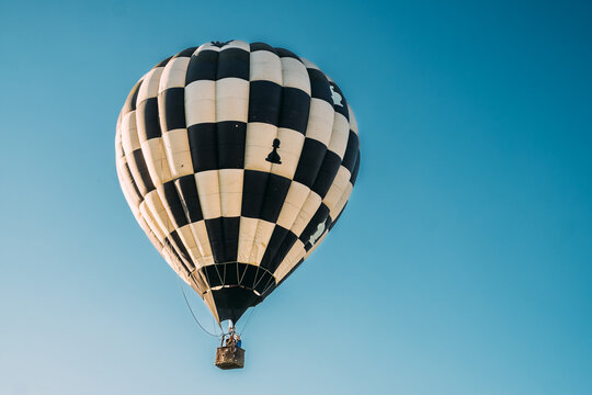 View of a checkered hot air balloon drifts gently through the clear, azure sky, a spectacle of adventure and serenity, Kikinda, Vojvodina, Serbia.