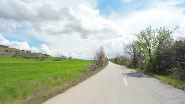 driving on rural road through fields in early spring
