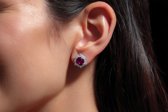 Woman wearing earrings with ruby and diamond details at close range