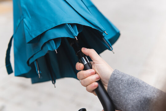 Person holding blue umbrella opening for rain protection