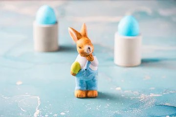 Cute decorative Easter bunny and blue easter eggs on a blue background © Daniela Baumann