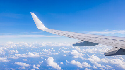Obraz premium Airplane wing over blue sky and clouds during flight showing passenger travel in aviation business journey.