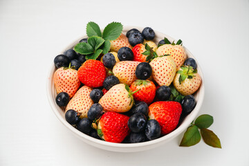Obraz premium Antioxidants and vitamins. Red and pink strawberries and fresh blueberries in a bowl, top view