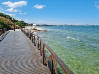 Naklejka premium Wooden bridge over the crystal-clear waters of a lagoon in Araruama, Brazil. Wooden walkway with old lighting posts.