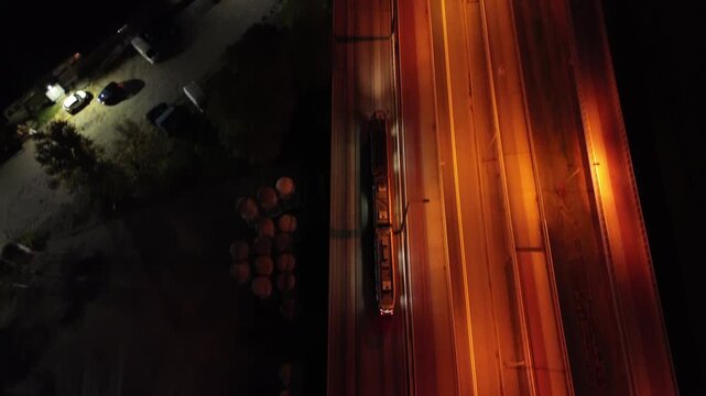 Tram glides through modern transport interchange at night, showcasing illuminated roads and roundabouts, with a dynamic aerial camera movement capturing the scene's progression and atmosphere