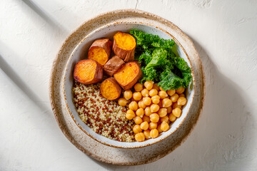 Fototapeta premium Vegan Buddha bowl with roasted sweet potato, quinoa, chickpeas and curly kale.
