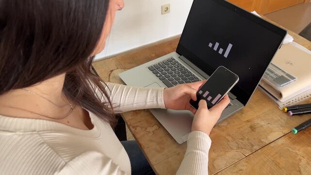 Joven profesional trabajando con smartphone y laptop a la vez