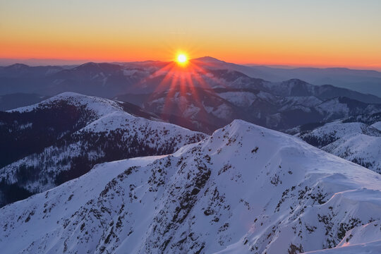 Aerial view of the sun's radiant glow kissing the snow-capped peaks of Dumbier in the Nizke Tatry mountains, Zilina Region, Slovakia.
