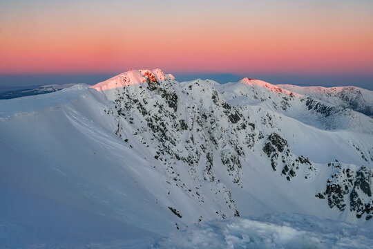 Aerial view of snow-capped peaks kissed by the warm glow of sunrise, Dumbier, Zilina Region, Slovakia.