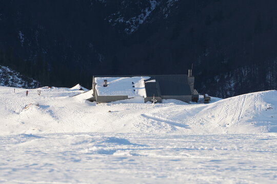 Aerial view of a snow-blanketed chalet nestled in the stark white landscape against the dark, looming mountains, Nizke Tatry, Slovakia.