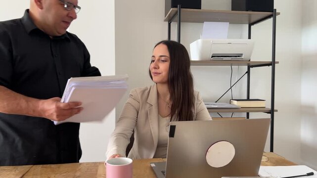 Compa&ntilde;ero de equipo entregando documentos a joven profesional