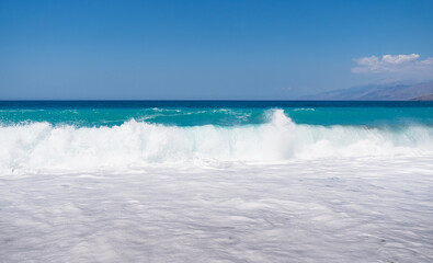 Fototapeta premium A landscape with waves of the blue Mediterranean Sea crashing onto a sandy beach