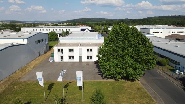Low aerial slide across industrial filter factory with waving flags