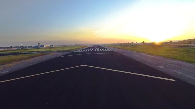 Forward aerial view from landing aircraft at sunset (or sunrise) from just before touchdown to rollout from runway.