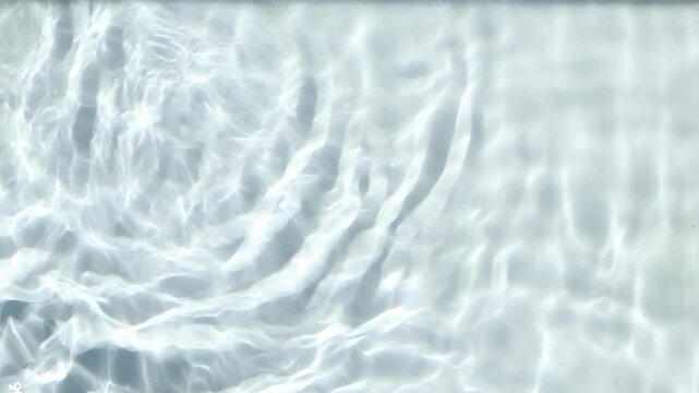 Abstract close-up of clear water surface in bright sunlight, where soft ripple rings expand, overlap and drift continuously from frame to frame, creating a clean shimmering background texture.