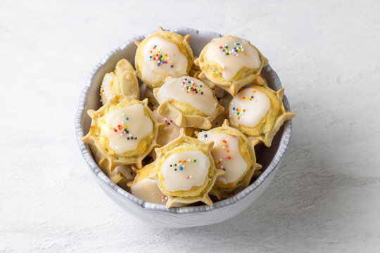 Traditional Sardinian ricotta cheese cookies with sugar glaze and sprinkles in ceramic bowl on white background