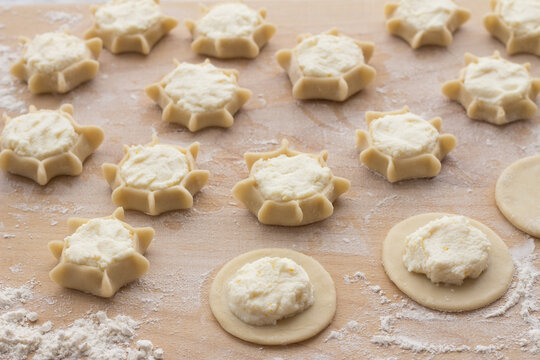 Preparation of Italian ricotta pastries showing dough circles and formed star shapes on floured wooden board