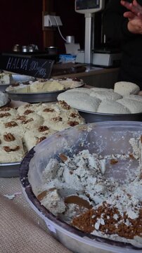 Vertical screen Easter market food display with traditional halva desserts topped with nuts sweet treats on street stall festive spring atmosphere local cuisine