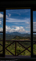 Fototapeta premium Panoramic Mountain View Framed by Balcony Window Under Blue Sky