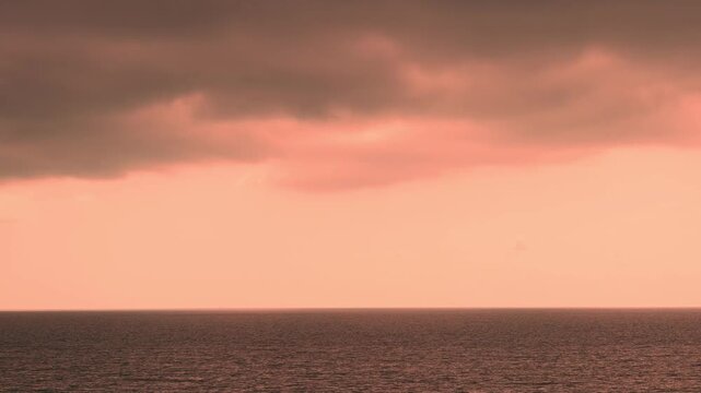 Coloful orange pink evening sky with storm dark thunderclouds over the sea time lapse. Overcast tropical sunset skyscraper dark clouds 4K ocean timelapse, slow motion, weather, humid
