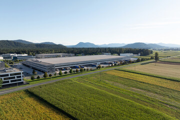 Naklejka premium The aerial view shows a logistics center with warehouse buildings, loading docks, and trucks. Supplies move through the transport hub.