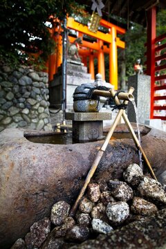 Shinto shrine purification basin with bamboo ladles and torii