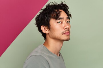 Fototapeta premium Young asian man gazing sideways in geometric studio setting
